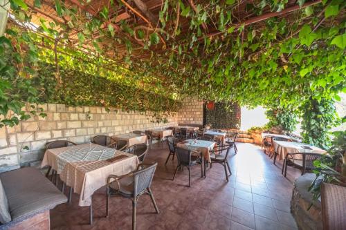 a restaurant with tables and chairs and vines at Apartments Pod Lozom with Seaview in Petrovac na Moru