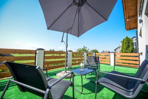 a patio with chairs and a table with an umbrella at Apartamenty Pawełek in Zator
