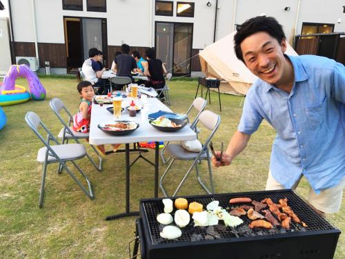 a man standing in front of a barbecue grill at Racine Home Harie in Takashima