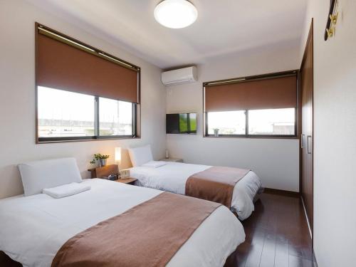 two beds in a room with two windows at Racine Home Harie in Takashima