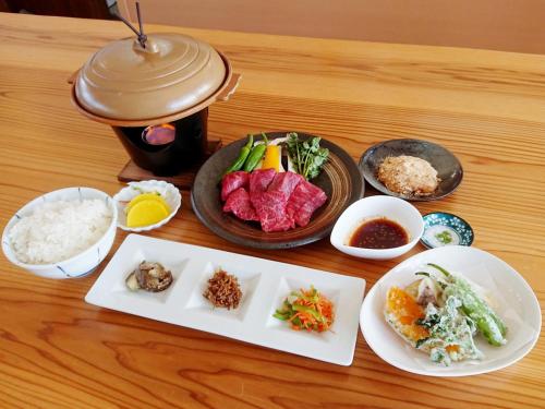 a table with plates of food and bowls of rice at Racine Home Harie in Takashima