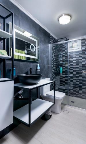 a black bathroom with a sink and a toilet at AlexandRos Home in Áyioi Dhéka