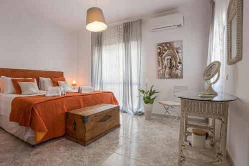 ein Schlafzimmer mit einem Bett mit einer orangefarbenen Decke und einem Tisch in der Unterkunft Villa Casa Rosina in Ferragudo