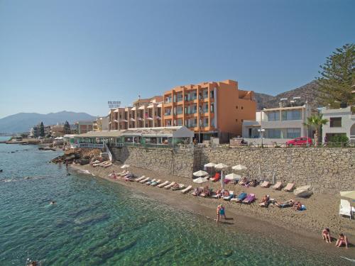 a beach with people sitting and standing on it at Palmera Beach Hotel & Spa - Adults Only in Hersonissos