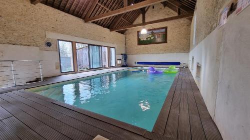 une grande piscine intérieure dans un immeuble dans l'établissement La Fresnée chambres d'hôtes, à Mosles