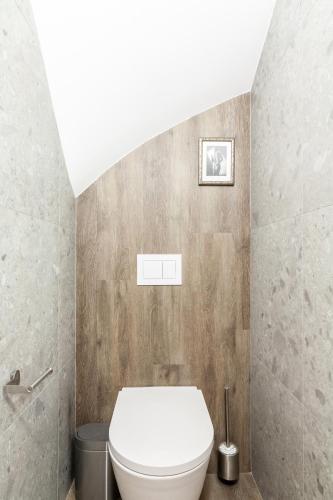 a bathroom with a white toilet in a room at Karklė Living Apartments, By Cohost in Karklė
