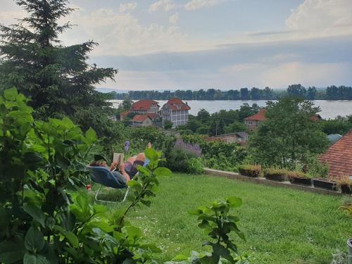 two people sitting in a yard with a view of the water at HostelChe Guest House in Smederevo