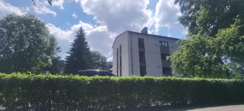 a building with a car parked in front of a hedge at APARTAMENTY ZDROJOWA 9 in Duszniki Zdrój
