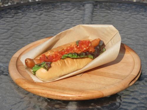 a hot dog on a wooden plate on a table at DogrunCafe & Resorts JENNIE West-Karuizawa in Miyota