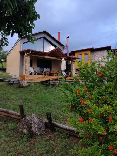 a house with a porch and a yard with flowers at DIMITRA's VILLAS in Elatochori