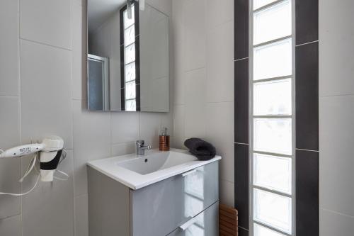 een witte badkamer met een wastafel en een spiegel bij CENTRE Appt 2 Chambres, Linge, Parking, Wifi in Vannes