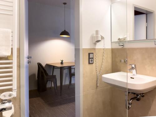 ein Badezimmer mit einem Waschbecken und einem Tisch in der Unterkunft Five Elements Hostel Leipzig in Leipzig