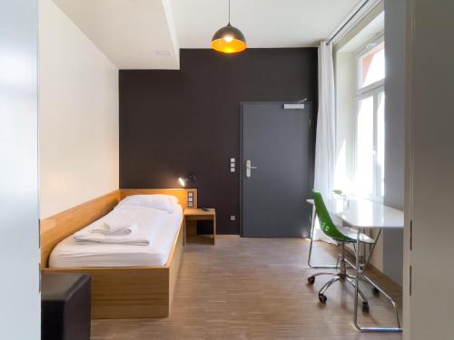 a bedroom with a bed and a desk and a window at Five Elements Hostel Leipzig in Leipzig