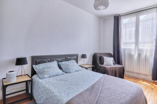 een slaapkamer met een bed, een stoel en een raam bij CENTRE Appt 2 Chambres, Linge, Parking, Wifi in Vannes