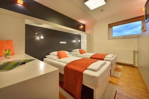 a bedroom with two beds and a desk and a window at Omnia Hotel Relax & Wellness in Janske Lazne