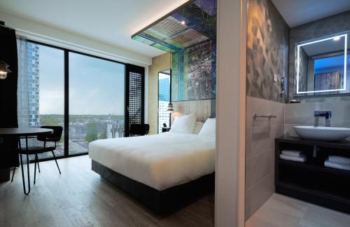 a bedroom with a bed and a sink and a bathroom at Inntel Hotels Utrecht Centre in Utrecht