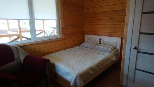 フジュルにあるGuesthouse Lazarevykhの木製の部屋にベッド1台が備わるベッドルーム1室があります。