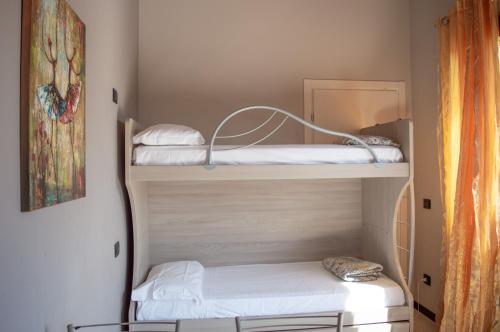 a room with three bunk beds with white sheets at La Valle Dei Caprioli Village Bungalow Park - Freelandia Azienda Agricola in Montescudo