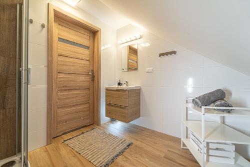 a bathroom with a wooden door and a sink at Apartament Rodzinny PlusPlus Mountain Aparts in Świeradów-Zdrój