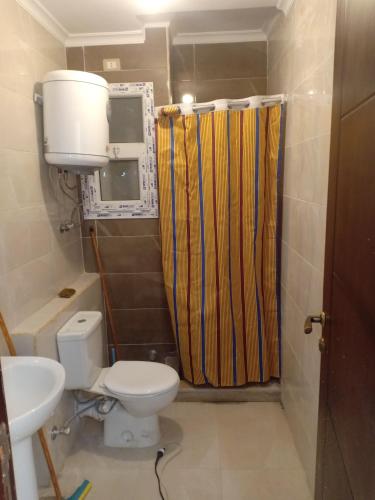 a bathroom with a toilet and a yellow shower curtain at chalet 9 porto golf marina Egyptian only in El Alamein