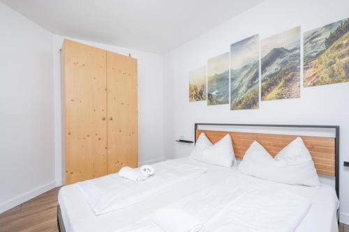 1 dormitorio con cama blanca y almohadas blancas en Alpen Apartment + Sauna und Netflix en Piesendorf