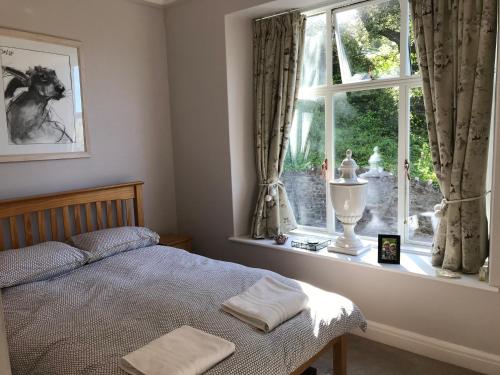 a bedroom with a bed in front of a window at 2 bed apartment overlooking North Sands beach in Salcombe