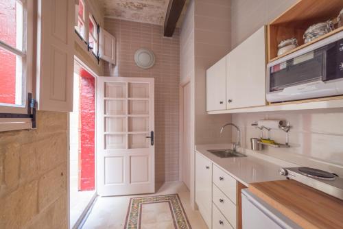a kitchen with white cabinets and a sink and a door at Casa San Carlo in Valletta