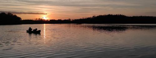 two people in a boat on a lake at sunset at Lacustra Cabanes accessibles en canoé et Chalets tout confort in Flayat