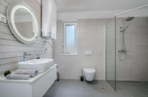 łazienka z umywalką, toaletą i lustrem w obiekcie Apartments Villa "Aurea" with pool w Krku