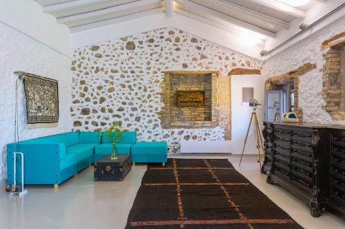 The Storage House في Danilia: غرفة معيشة مع أريكة زرقاء وجدار حجري