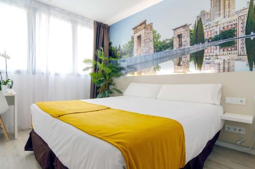 a bedroom with a large bed with a yellow blanket on it at Hotel BESTPRICE Alcalá in Madrid