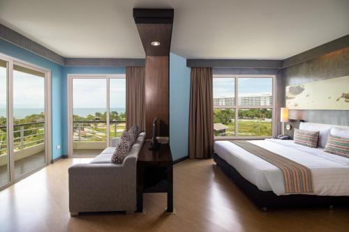 a bedroom with a bed and a couch and windows at Sila at Hua Hin Serviced Apartment & Hotel in Hua Hin