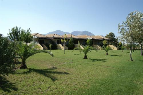 a house with palm trees in front of a yard at Odysseas rooms in Kalón Nerón