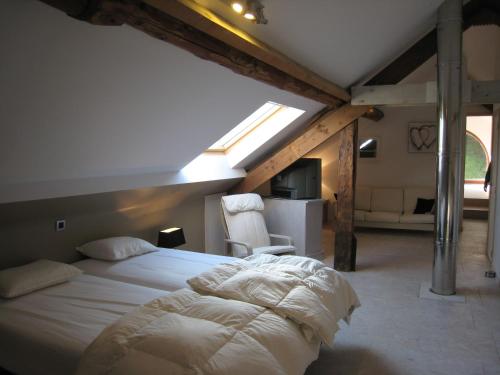 a bedroom with a bed and a chair in a attic at Gite Kooa in Theux