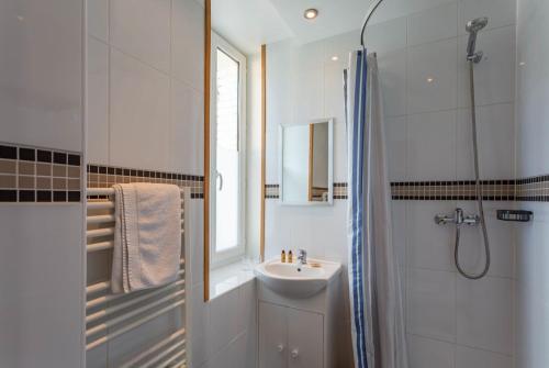 ein weißes Bad mit einem Waschbecken und einer Dusche in der Unterkunft Hotel Les Aravis in Saint-Jean-de-Sixt