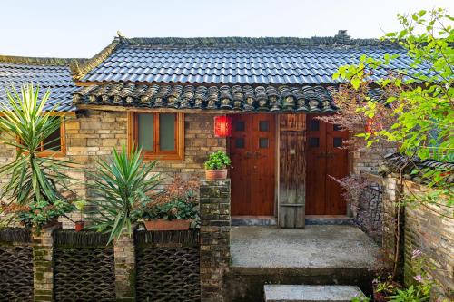 a brick house with a wooden door in a garden at Yangshuo Secret Garden in Yangshuo