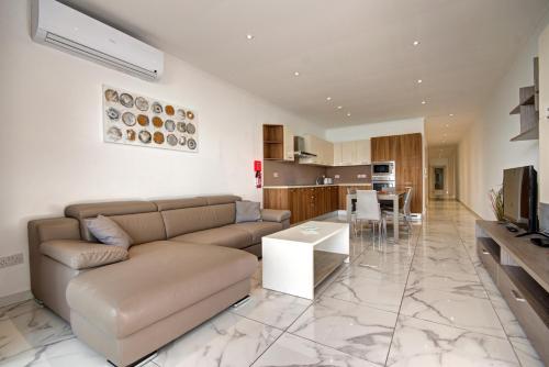 a living room with a couch and a kitchen at Malta's Beachfront Apartment in Mellieha in Mellieħa