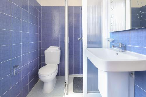 a blue tiled bathroom with a toilet and a sink at Ta Gianni Guest House in Sliema