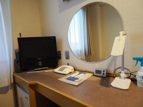 a desk with a computer monitor and a telephone on it at 大村ヤスダオーシャンホテル in Omura