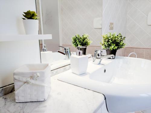 un bagno bianco con due lavandini e uno specchio di Appartamento Funtanedda - Affitti Brevi Italia a Triei