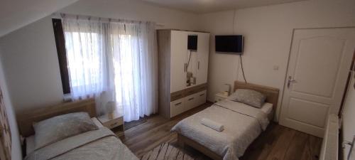 1 dormitorio con 2 camas, TV y ventana en Apartman Majetić en Otočac