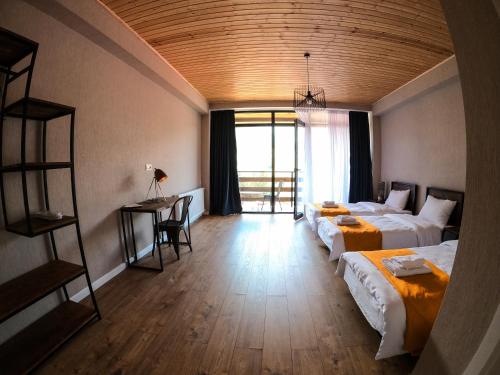 a bedroom with two beds and a desk and a window at Capra Hotel Kazbegi in Stepantsminda