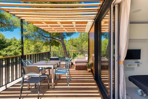a deck with a table and chairs on a balcony at Kamp Vira Mobile Homes in Hvar