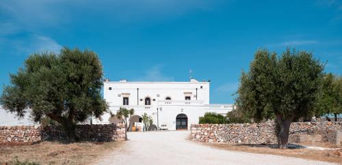 a white building with two trees in front of it at Masseria Donna Nina in Ostuni