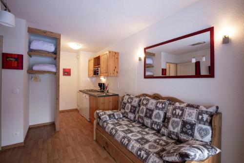 Una sala de estar con un sofá y un espejo. en Florence 2 103 - FAMILLE appart 4 pers Valfréjus, en Valfréjus