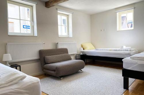 1 dormitorio con silla, 1 cama y ventanas en Charmante Apartments mit TV-WiFi en Kelkheim (Taunus)