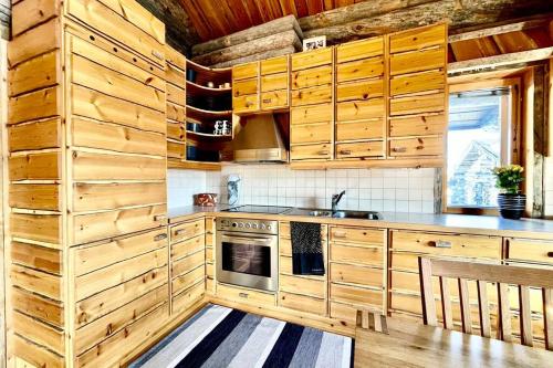 a kitchen with wooden cabinets and a stove at Ruka View at the Slopes Ski in, Family & Bike Park, National Park, hike trails - Lapland Villas in Ruka
