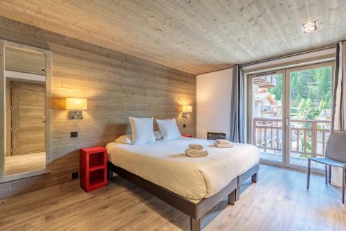 een slaapkamer met een groot bed en een groot raam bij Victoria Lodge, Friendly Hotel in Val dʼIsère