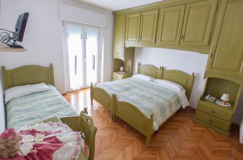 a bedroom with two beds and a cabinet at Albergo Italia in Molveno