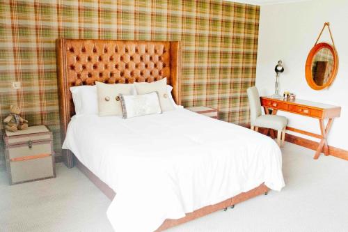 a bedroom with a large white bed and a desk at Hideaway Lodge in Kingussie